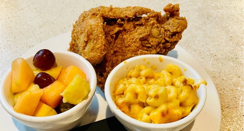 Fried chicken, mac and cheese, and fresh fruit in a bowl