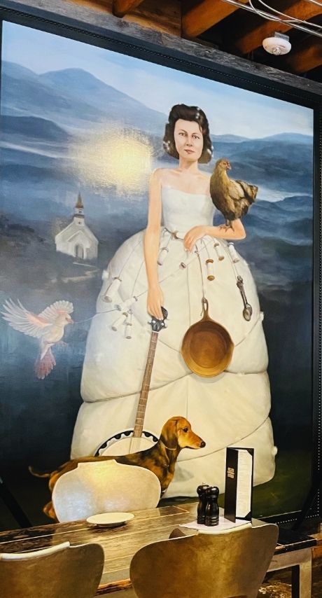 Large portrait of Nellie Jonas in a dress with a chicken, frying pan, and banjo.