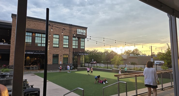 Kids running and playing on the outdoor turf play area at sunset at Hobo's restaurant in Rock Hill SC